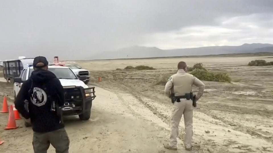 CORRECTS THAT THE SOURCE IS STRINGR, NOT REBECCA BARGER - In this image from video provided by Stringr, a law enforcement officer and others look at the clouds and landscape outside the Burning Man festival site in Black Rock, Nev., on Monday, Sept. 4, 2023. An unusual late-summer storm stranded thousands at the week-long event. (Stringr via AP)