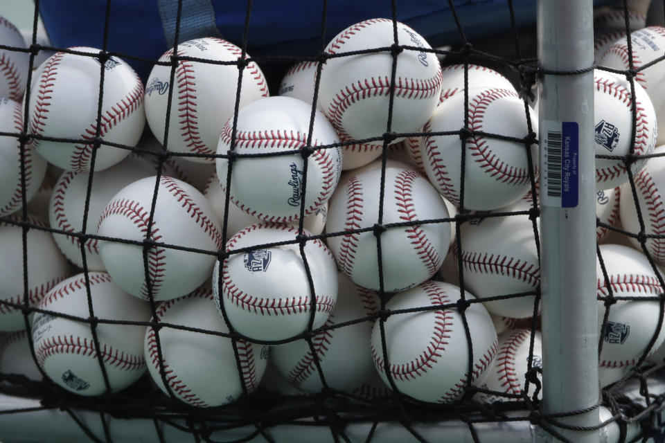 Balls marked with Cactus League spring training logos are seen in a basket during Kansas City Royals baseball practice at Kauffman Stadium Friday, July 3, 2020 in Kansas City, Mo. (AP Photo/Charlie Riedel)