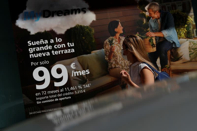 A woman walks past a poster advertising Caixabank’s consumer financing programme "MyDreams" in Madrid