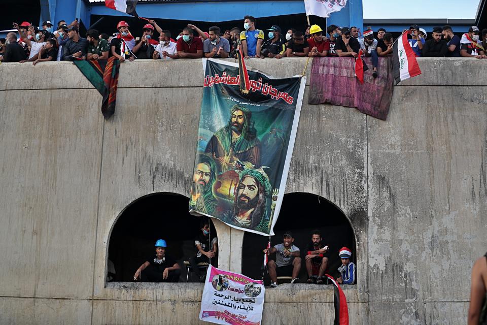 Anti-government protesters place posters of Shiite clerics on a building during ongoing protests in Baghdad, Iraq, Wednesday, Oct. 30, 2019. (AP Photo/Khalid Mohammed)