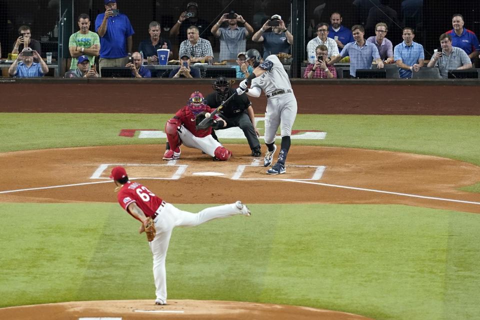 New York Yankees' Aaron Judge connects for a solo home run, his 62nd of the season, off of Texas Rangers starting pitcher Jesus Tinoco (63) as Texas Rangers catcher Sam Huff and umpire Randy Rosenberg look on in the first inning of the second baseball game of a doubleheader in Arlington, Texas, Tuesday, Oct. 4, 2022. With the home run, Judge set the AL record for home runs in a season, passing Roger Maris. (AP Photo/Tony Gutierrez)