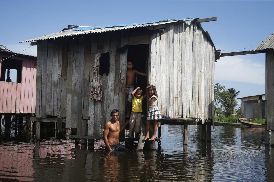FILE - Francisco Fabiano Rodrigues and his children stand outside their home on a street flooded by the rise of the Negro River in Iranduba, Amazonas state, Brazil, May 23, 2022. The two-day Amazon Summit opens Tuesday, Aug. 8, 2023, in Belem, where Brazil hosts policymakers and others to discuss how to tackle the immense challenges of protecting the Amazon and stemming the worst of climate change. (AP Photo/Edmar Barros, File)