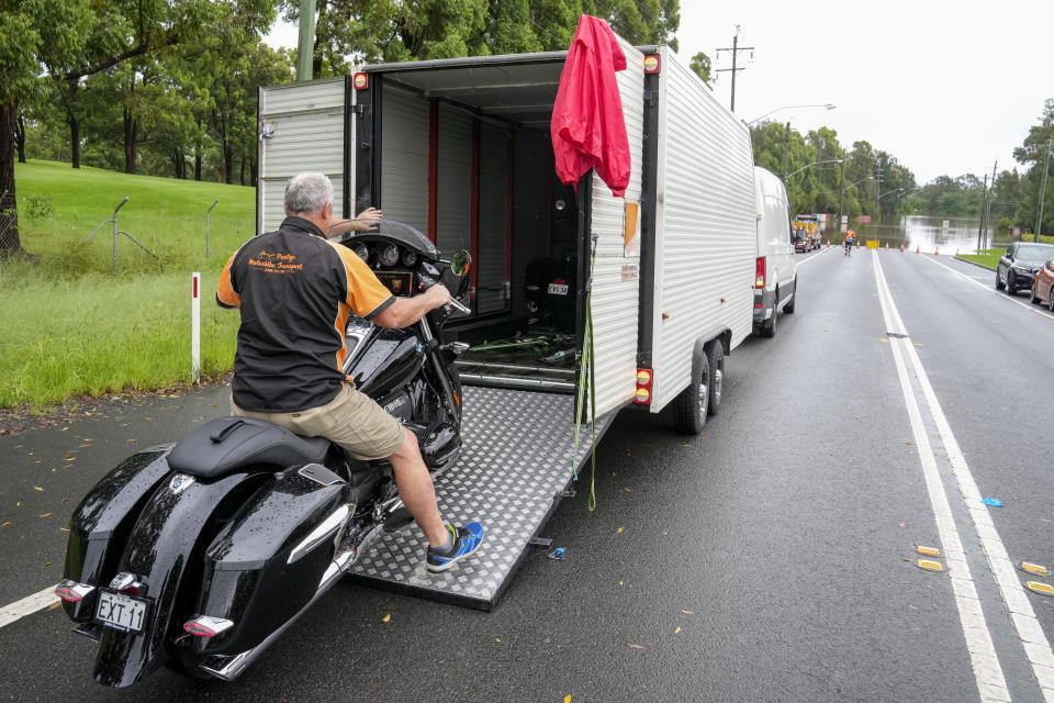 Paul Swinfield loads his BMW motorbike into a truck as he escapes the floods on the outskirts of Sydney, Australia, Thursday, March 3, 2022.Tens of thousands of people had been ordered to evacuate their homes and many more had been told to prepare to flee as parts of Australia's southeast coast are inundated by the worst flooding in decades. (AP Photo/Rick Rycroft)