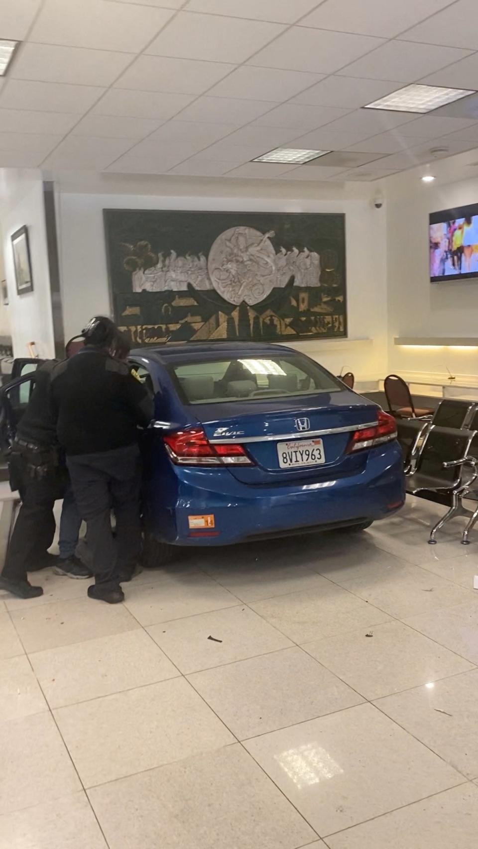 Security personnel respond to the driver of a car which crashed into the Chinese consulate in San Francisco (Sergii via REUTERS)