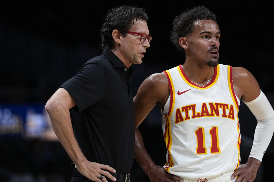 Atlanta Hawks head coach Quin Snyder talks with guard Trae Young (11) during the first half of a preseason NBA basketball game against the Cleveland Cavaliers Tuesday, Oct. 10, 2023, in Atlanta. (AP Photo/John Bazemore)