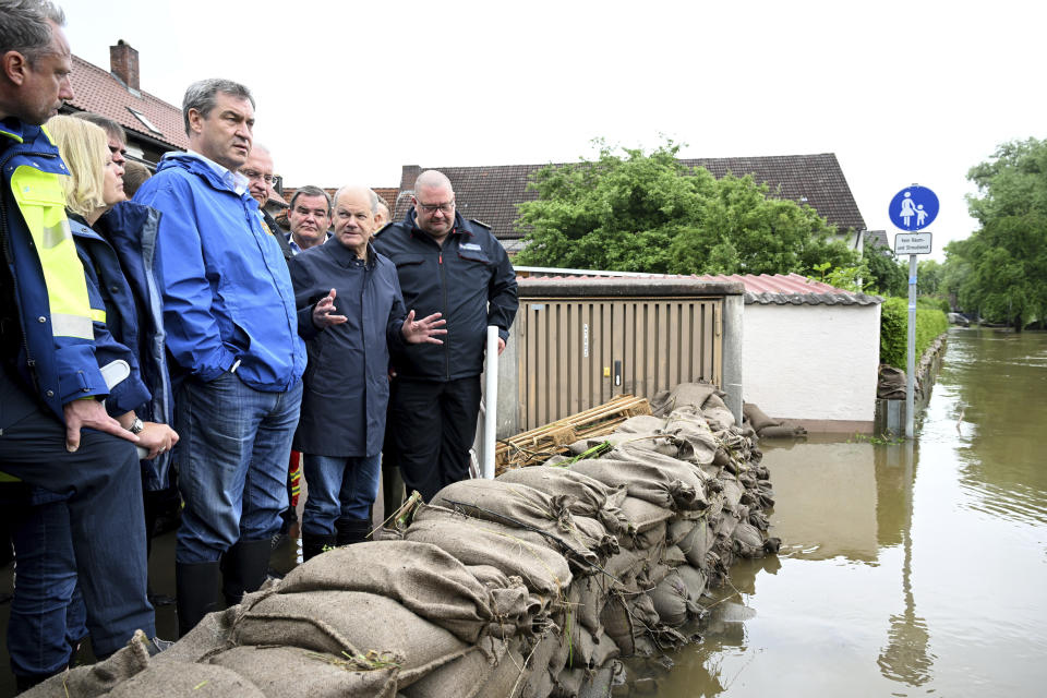 German Federal Chancellor Olaf Scholz, fourth left, Bavarian Prime Minister Markus S'der, third left, Bavarian and German Federal Interior Minister Nancy Faeser, second left, stand behind a barrier of filled sandbags during a site inspection in Reichertshofen, Upper Bavaria, Germany, Monday, June 3, 2024, after flooding in the area. (Sven Hoppe/dpa via AP)