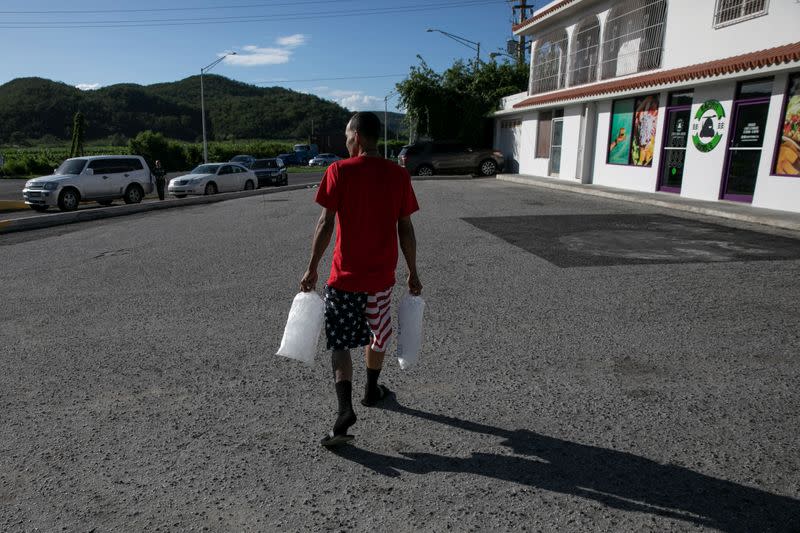 A man carries bags of ice at a gas station after an earthquake in Guanica