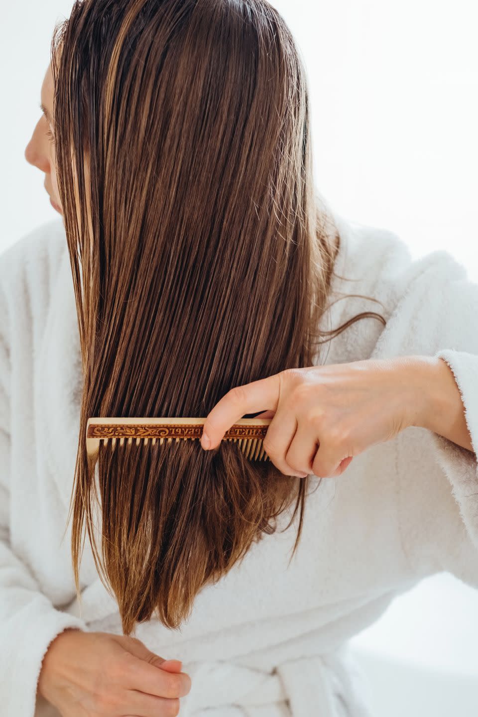 girl carefully combing her hair with a wooden comb
