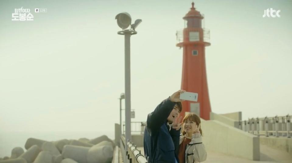 Couple taking picture in front of lighthouse