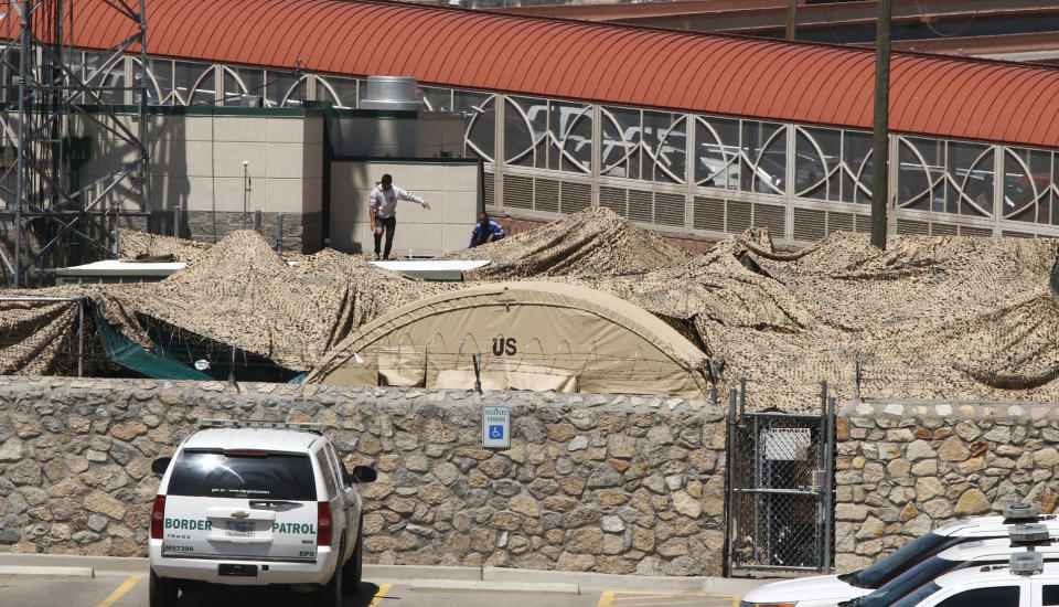 In this June 7, 2019, photo, migrants adjust a shade canopy over an outdoor encampment where they're waiting to be processed by immigration in El Paso, Texas. The Trump administration is facing growing complaints from migrants about severe overcrowding, meager food and other hardships at border holding centers like this one. (AP Photo/Cedar Attanasio)