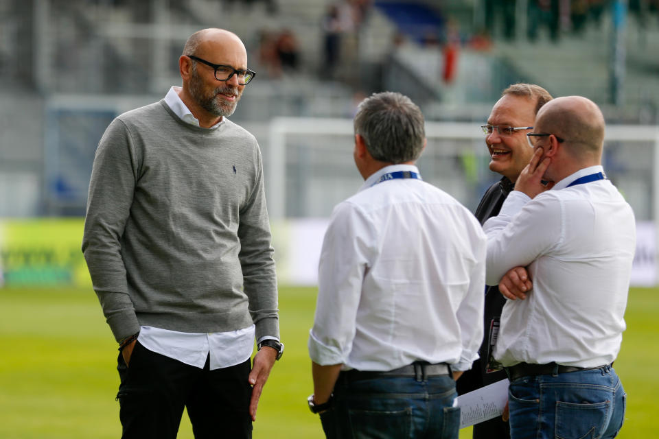 El presidente del Wiesbaden, Markus Hankammer, conversando con un grupo de personas en el césped del estadio antes de un partido.