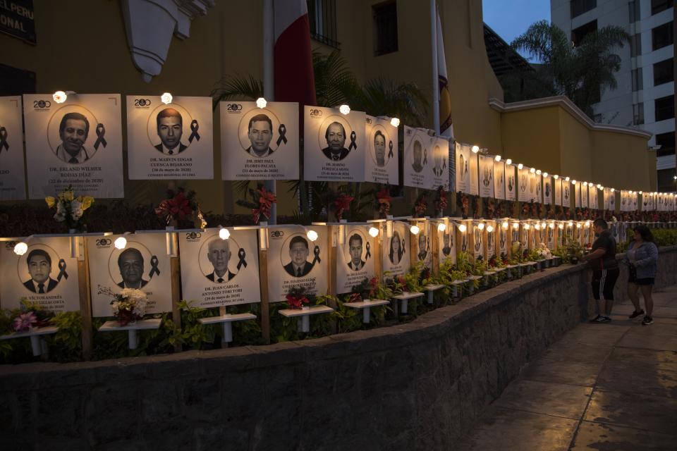 Relatives leave flowers on the portrait of Jorge Luis Casana, 62, a doctor who died due to the new coronavirus in Lima, Peru, Tuesday, Jan. 19, 2021. The Peruvian Medical College reported that at least 11 doctors have died during the first days of 2021. (AP Photo/Rodrigo Abd)