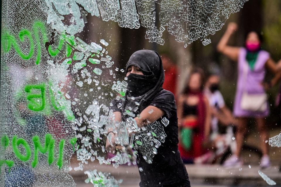 A woman breaks a glass at the entrance of Hidalgo metro station during a demonstration to commemorate the International Women's Day in Mexico City, on March 8, 2021. (Photo by PEDRO PARDO / AFP) (Photo by PEDRO PARDO/AFP via Getty Images)