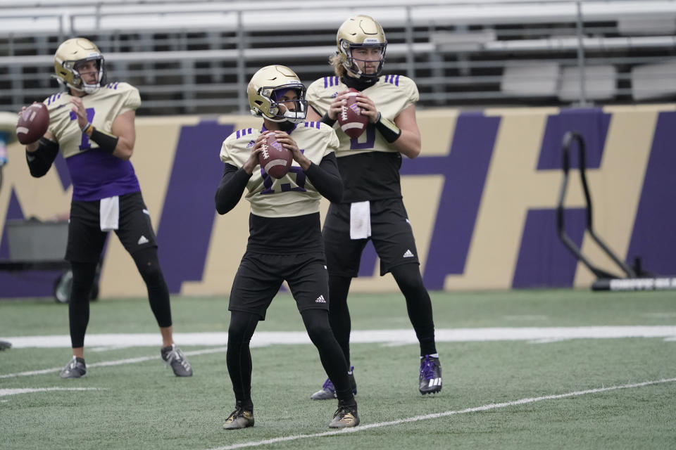 Washington quarterbacks Jaden Sheffey, center, Kevin Thomson, left, and Jacob Sirmon, right, pass in a group during NCAA college football practice, Friday, Oct. 16, 2020, in Seattle. (AP Photo/Ted S. Warren)