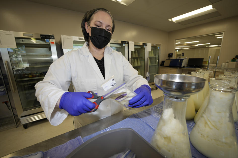 Rebecca Heinrich, director of the Mothers' Milk Bank, loads frozen milk donated by lactating mothers from plastic bags into bottles for distribution to babies Friday, May 13, 2022, at the foundation's headquarters in Arvada, Colo. (AP Photo/David Zalubowski)