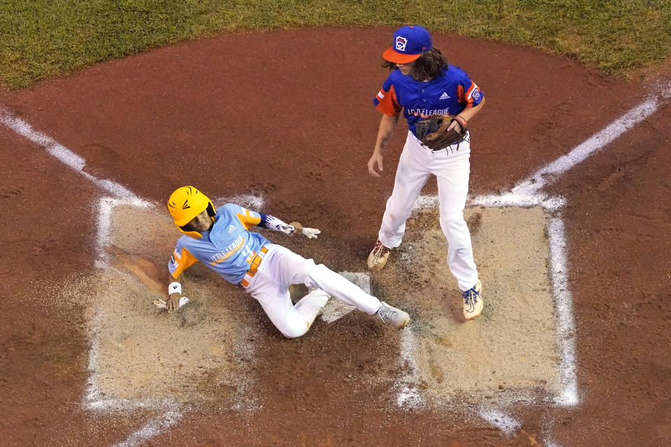 Honolulu's Kaikea Patoc-Young (9) scores on a wild pitch by Taylor, Mich.'s Ethan Van Belle, right, during the first inning of a baseball game at the Little League World Series in South Williamsport, Pa., Wednesday, Aug. 25, 2021. Hawaii won 2-0. (AP Photo/Gene J. Puskar)