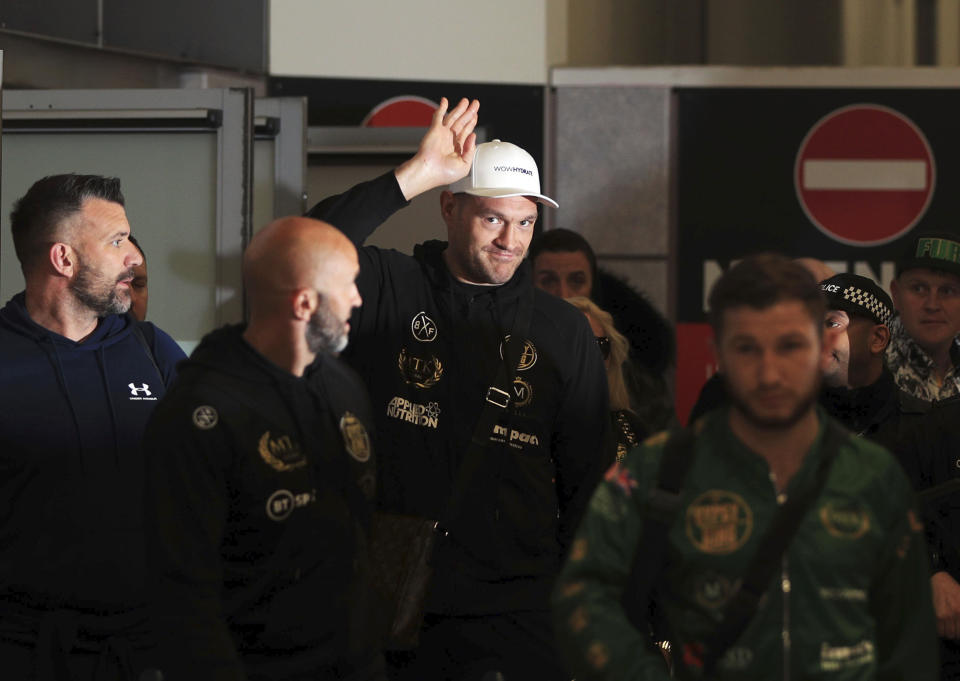 British boxer Tyson Fury acknowledges the crowd at Manchester Airport, in Manchester, England, Tuesday, Feb. 25, 2020. Fury returned to the UK after beating Deontay Wilder in Las Vegas last Saturday to become WBC heavyweight world champion. Wilder says an elaborate outfit he wore on his ring walk wore him down so much that he didn't have the legs to withstand Tyson Fury in their heavyweight title fight. Wilder also told The Associated Press he would execute a clause in his contract for a third fight with Fury. (Peter Byrne/PA via AP)