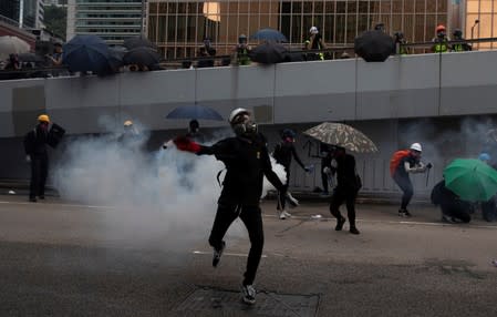 A demonstrator throws back a tear gas shell at the police during a protest in Hong Kong