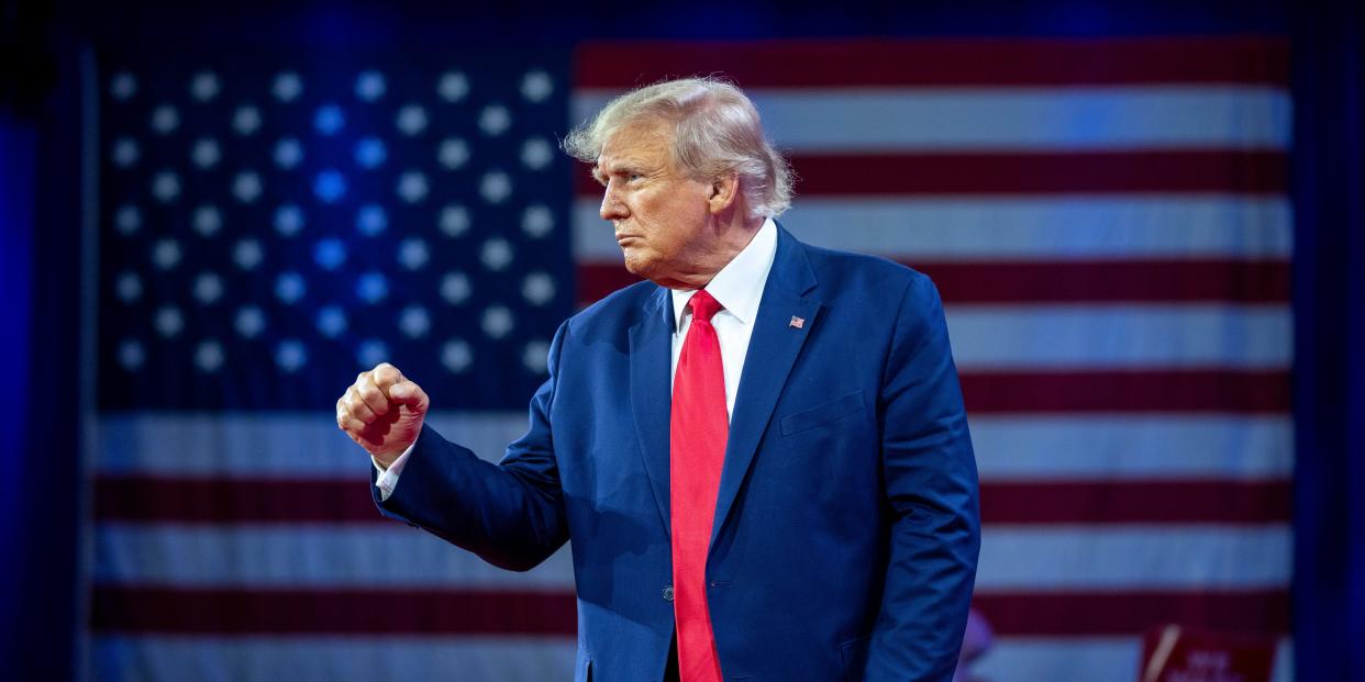 Donald Trump raising his fist in front of American flag.