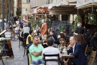 People sit at outdoor tables as they enjoy a drink on a Friday evening, in Rome's Campo dei Fiori square, Friday, May 22, 2020. Since Monday, Italians have regained freedoms, including being able to sit down at a cafe or restaurant, shop in all retail stores or attend church services such as Mass after a partial lifting of restriction measures aimed at containing the spread of COVID-19. (AP Photo/Andrew Medichini)