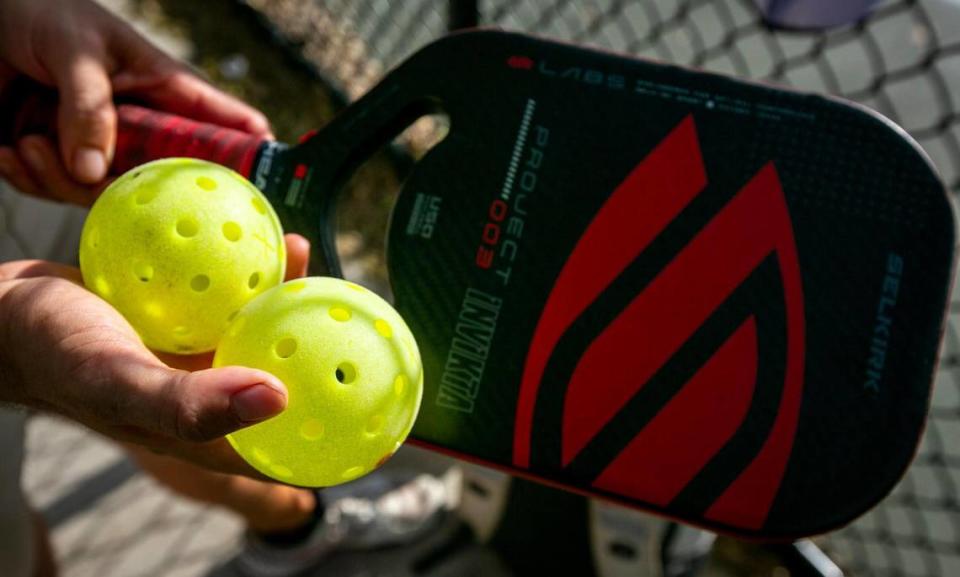 Brian Dreher shows a pickleball paddle and balls at the pickleball courts in Tropical Park on March 23, 2023.