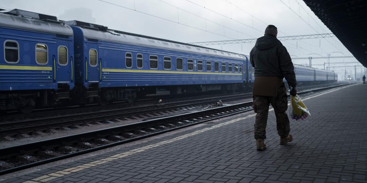 Ukrainian soldier Vasyl Khomko, 42, carries flowers as he waits for his wife and daughter at the train station in Kyiv, Ukraine, Saturday, Dec. 31, 2022.