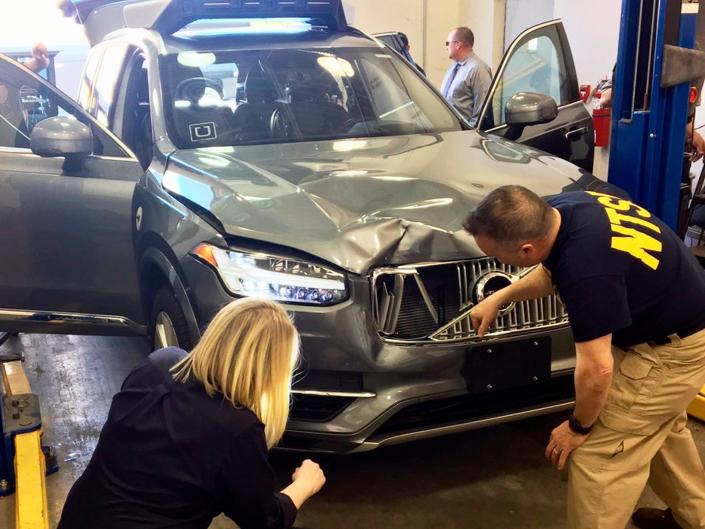 Investigators examine a self-driving Uber SUV that struck a woman in Tempe, Arizona.