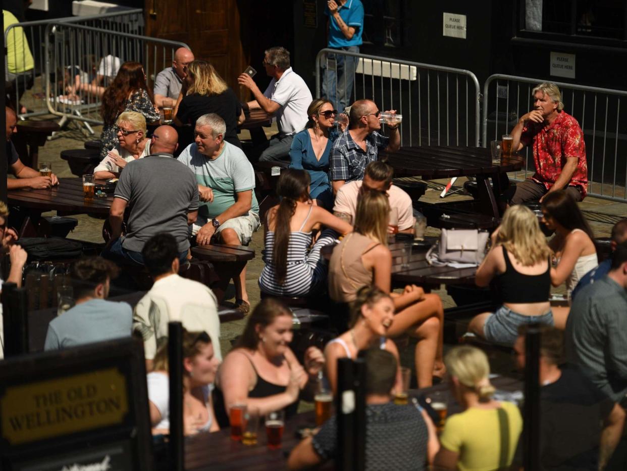 People sit with drinks at outdoor seating at a pub in the centre of Manchester, northwest England: AFP via Getty Images