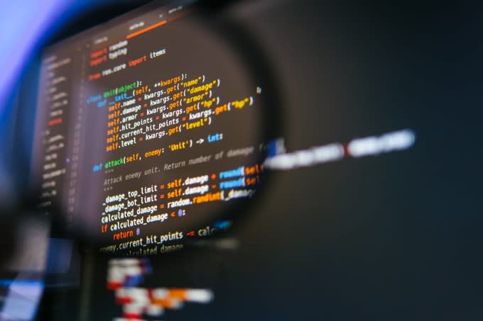 Open source code on a computer screen highlighted by a magnifying glass.