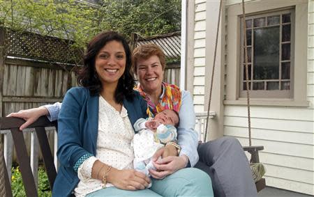 Valeria Tanco (L), and Sophy Jesty pose with their new baby girl, Emilia, at their home in Knoxville, Tennessee April 7, 2014. REUTERS/Wade Payne