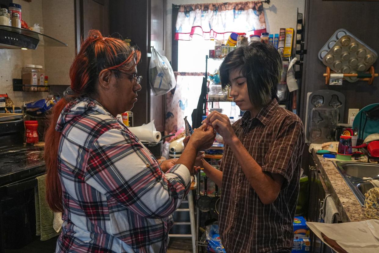 Betty Patina-Trujillo helps her son, Margarito "Mars" Patina-Trujillo, with a drink in their home. Margarito, 14, was born with three congenital heart defects and had surgery this fall for scoliosis.