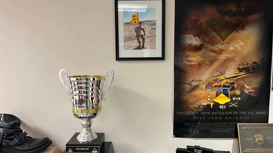 A portrait of Spc. Wyatt Thyfault hangs in the headquarters offices of Battle Company, 1st Battalion, 66th Armor Regiment, at Fort Carson, Colorado. The trophy in the center-left of the Feb. 27, 2024 photograph is the Sullivan Cup trophy, which the company won in 2022 for having the Army's top tank crew. (Sgt. Collin Pattan/Army)