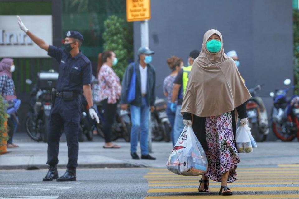 A shopper makes her way out of the Chow Kit wet market with her groceries in Kuala Lumpur March 27, 2020. ― Picture by Ahmad Zamzahuri