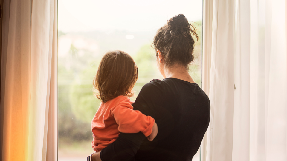 Cost of living: A mother and child look out a window.