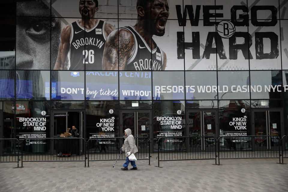 A pedestrian passes an entrance to the Barclays Center in the Brooklyn borough of New York on Thursday, March 12, 2020, after the NCAA's Atlantic 10 Conference Tournament was announced cancelled due to concerns over the COVID-19 coronavirus. (AP Photo/John Minchillo)