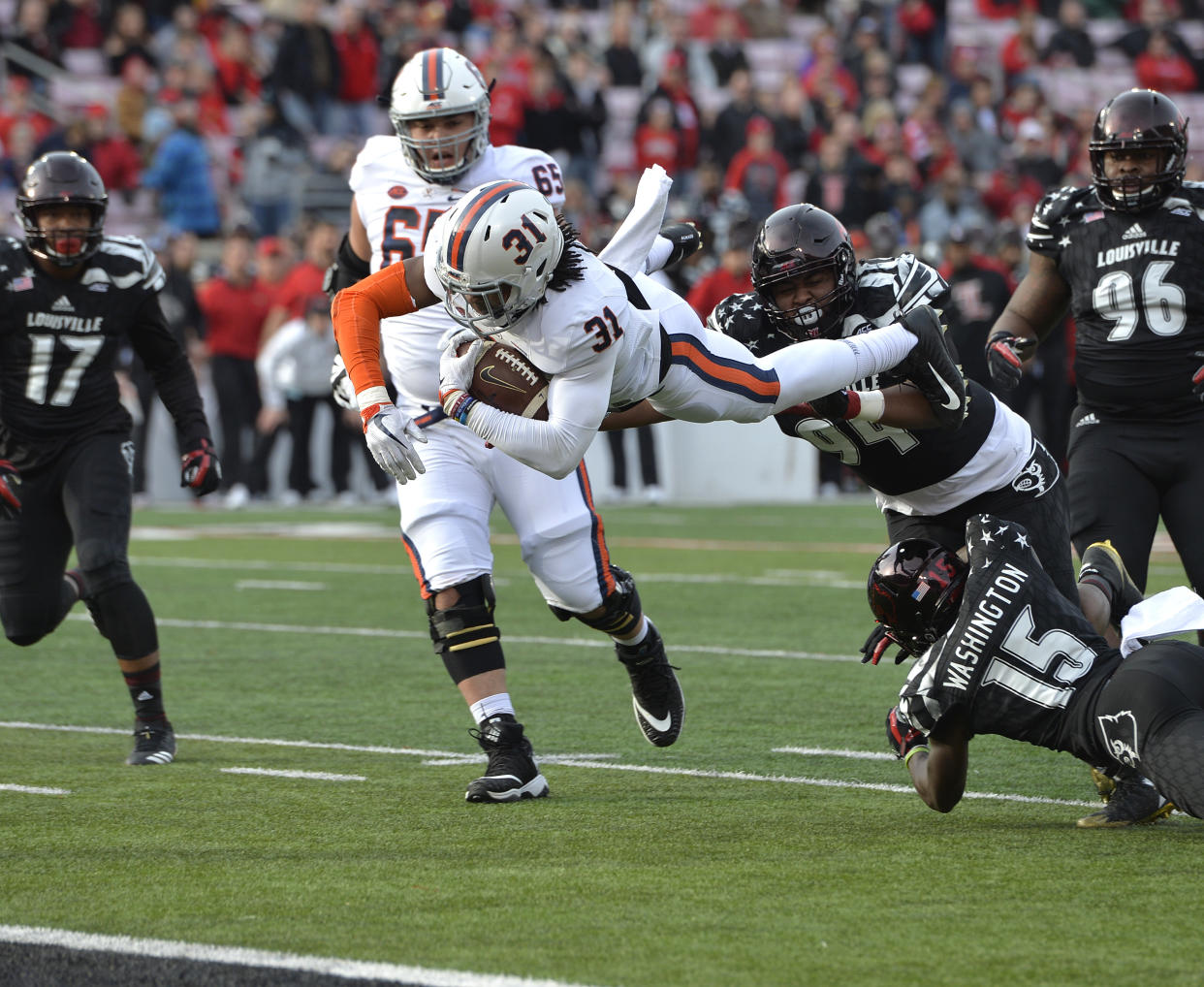 Virginia running back Chris Sharp (31) dives for the end zone over the defense of Louisville defensive tackle G.G. Robinson (94) and cornerback Trumaine Washington (15) during the first half of an NCAA college football game, Saturday, Nov. 11, 2017, in Louisville, Ky. (AP Photo/Timothy D. Easley)