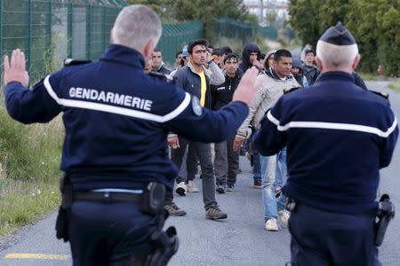 French gendarmes block migrants along a road to prevent them access to train tracks which lead to the Channel Tunnel in Frethun, near Calais, France, July 29, 2015. REUTERS/Pascal Rossignol