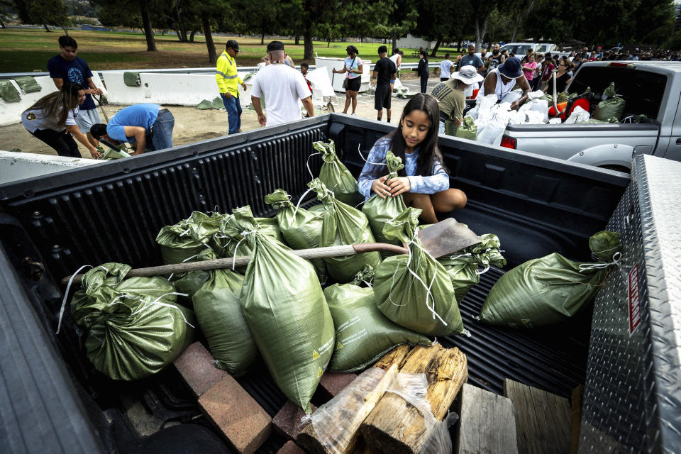 FILE - Madeline Noble, 9, sits in the back of her dad's pickup truck as she assists with sandbags at Wildwood Park in San Bernardino, Calif., on Aug. 19, 2023, as residents prepare for the arrival of Hurricane Hilary. Former Hurricane Hilary was actually no longer a tropical storm but essentially had the same impact when its destructive remnants entered California last August, according to a new National Hurricane Center report. (Watchara Phomicinda/The Orange County Register via AP, File)