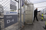 A Boeing worker walks out of a gate for a smoke break at an airplane manufacturing plant Wednesday, April 29, 2020, in Renton, Wash. Boeing says it will cut about 10% of its work force and slow production of planes as it deals with the ongoing grounding of its best-selling plane and the coronavirus pandemic. With air travel falling sharply because of the virus, airlines have delayed orders and deliveries of new planes, reducing Boeing's revenue. (AP Photo/Elaine Thompson)