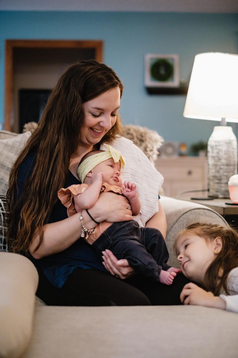 Alyssa Bostic holds 1-month-old daughter, Emryn, while 3-year-old Regan nuzzles her sister on Wednesday in the family's New Philadelphia home.