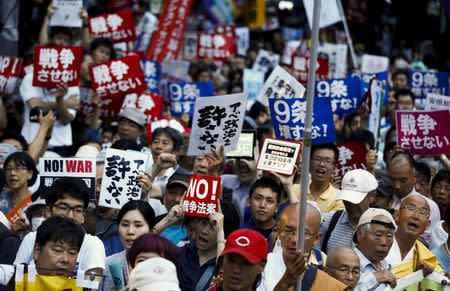 People hold placards during a protest against Japan's Prime Minister Shinzo Abe's security-related legislation outside the parliament building in Tokyo July 16, 2015. REUTERS/Thomas Peter