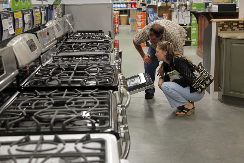 In this Monday, Sept. 10, 2012 photo Brian Gibson, top right, and his wife Elizabeth Gibson, below right, both of Framingham, Mass., examine stoves at a Lowe's store location in Framingham. U.S. companies remained cautious in September and held back on orders for long-lasting manufactured goods that signal investment plans. (AP Photo/Steven Senne)
