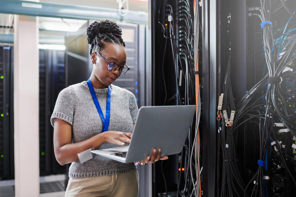 A female tech worker types on a laptop