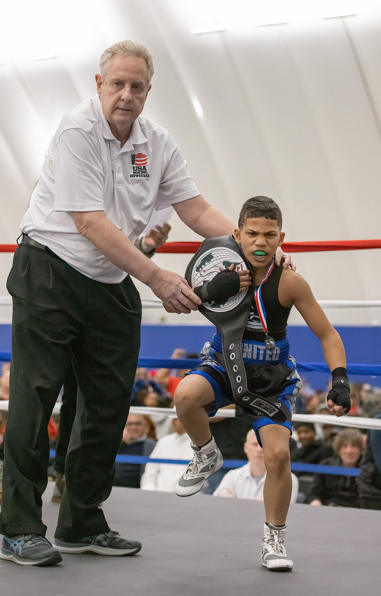 Khaine Charles, 9, of Canton, is presented the Peewee division title belt Saturday night by referee Tom Miller following his bout with Marvis Spencer, of Columbus, at Brawl at Hall of Fame Village.