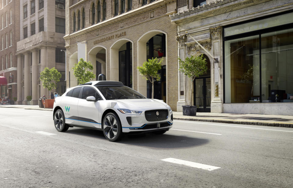 Jaguar I-PACE with a Waymo logo driving in the city