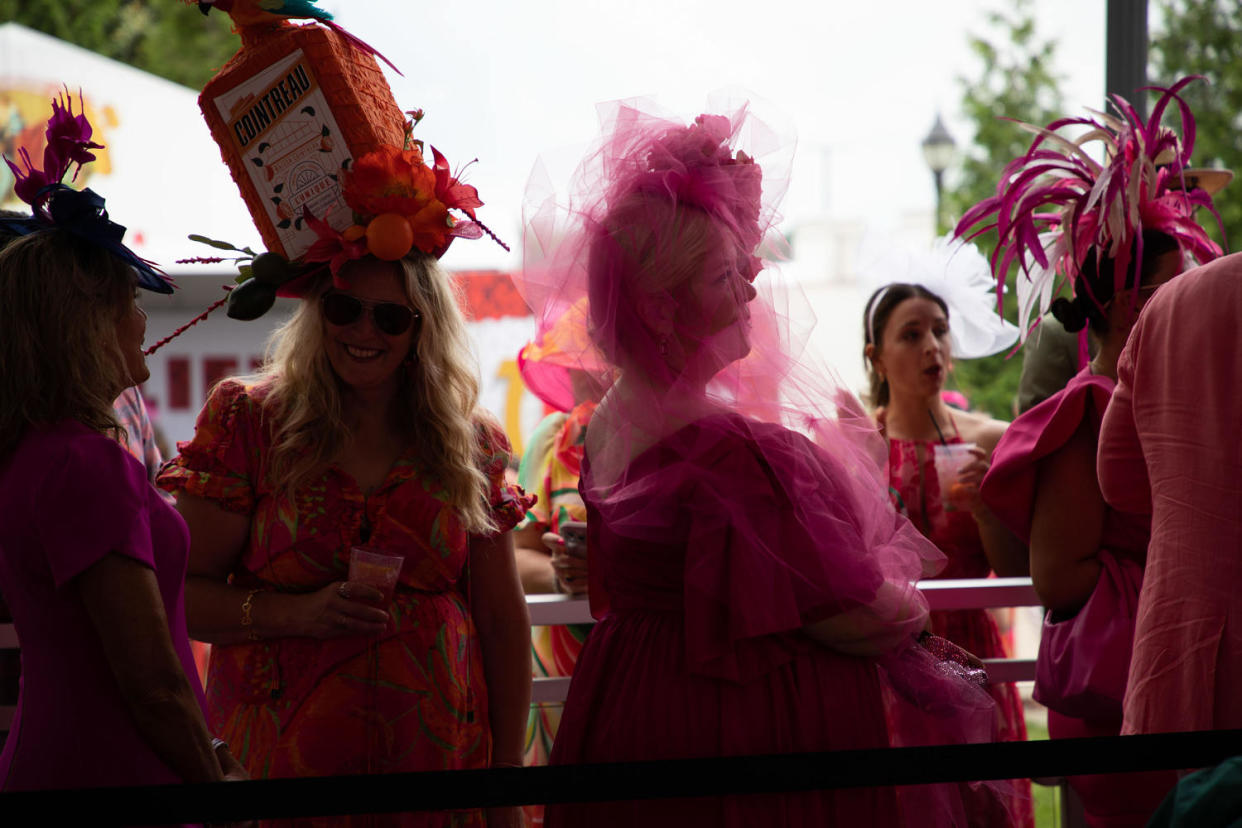 Women in large hats line up at Churchill Downs.