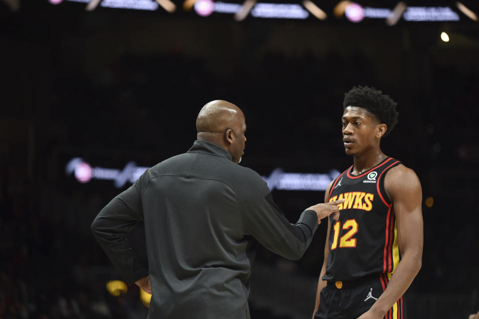 Atlanta Hawks head coach Nate McMillan, left, speaks to Atlanta Hawks forward De'Andre Hunter (12) during the first half of an NBA basketball game against the Miami Heat, Friday, Jan. 21, 2022, in Atlanta. (AP Photo/Hakim Wright Sr.)