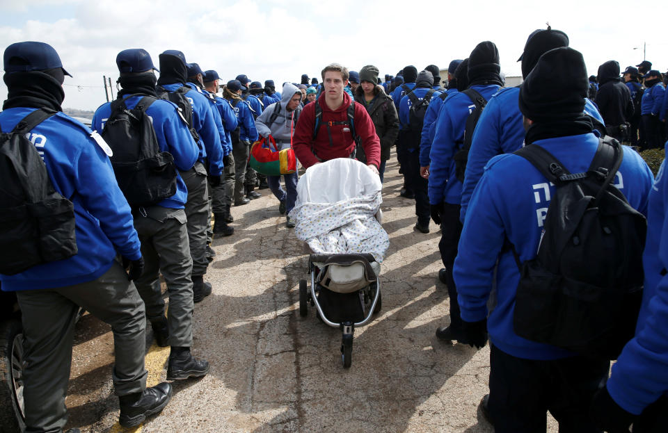 A family member of an Israeli settler family pushes a stroller past Israeli policemen during an eviction of residents from the Israeli settler outpost of Amona in the occupied West Bank February 1, 2017.&nbsp;