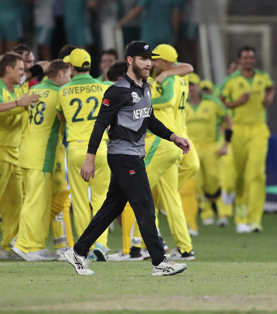 New Zealand's captain Kane Williamson walks past Australian cricketers celebrating their victory in the Cricket Twenty20 World Cup final match against New Zealand in Dubai, UAE, Sunday, Nov. 14, 2021. (AP Photo/Aijaz Rahi)