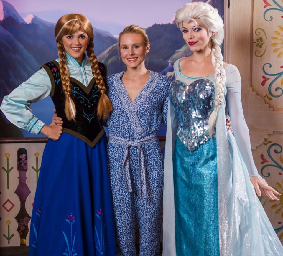 Kristen Bell (center) with Disney cast members dressed as her Frozen character Anna (left) and Elsa. | Steven Diaz/Disney Parks via Getty